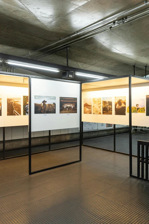 an empty room that has two black benches and a white wall with different pictures