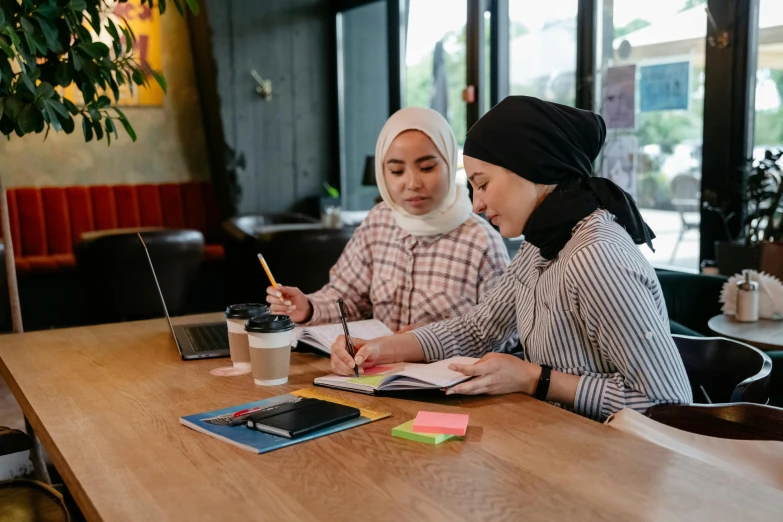 two women sit at a table and take notes