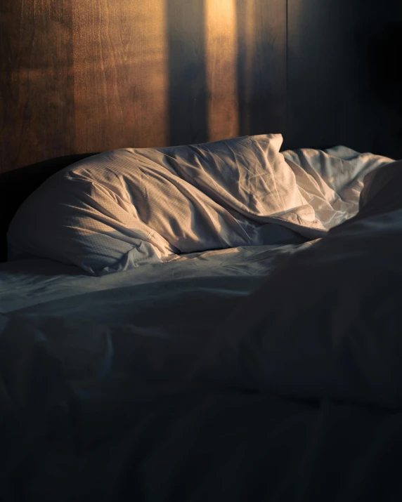 an unmade bed with white sheets and sheets pulled over