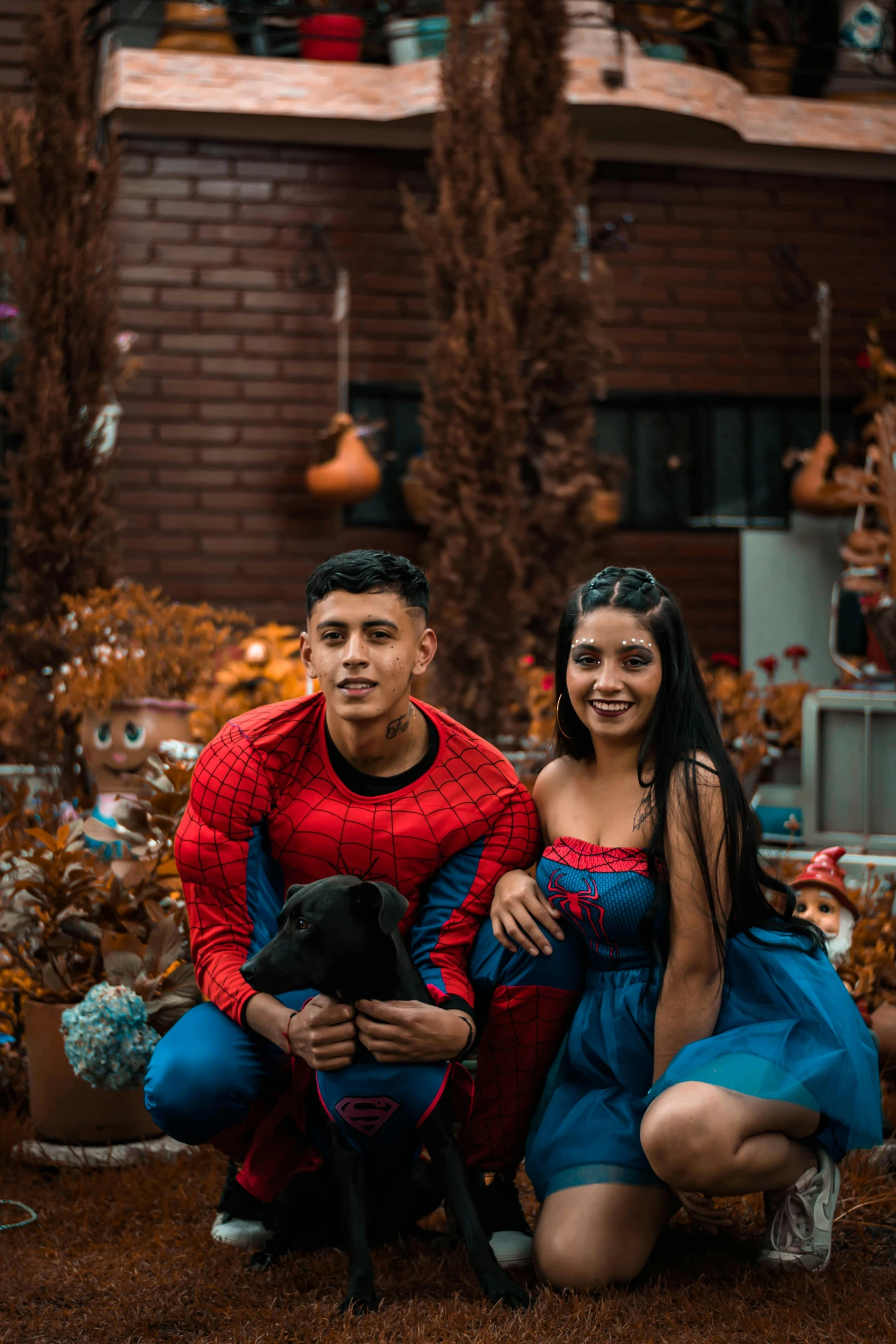 a young couple in spiderman costume standing next to a dog