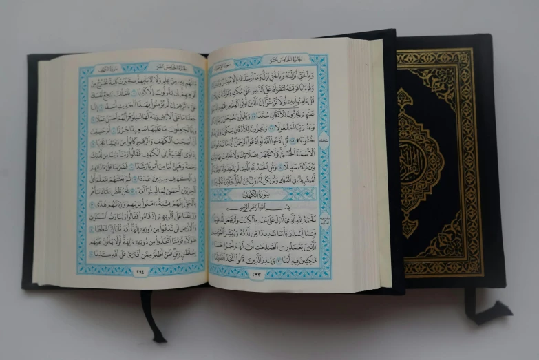 a book opened on a white background with a black binding and arabic writing