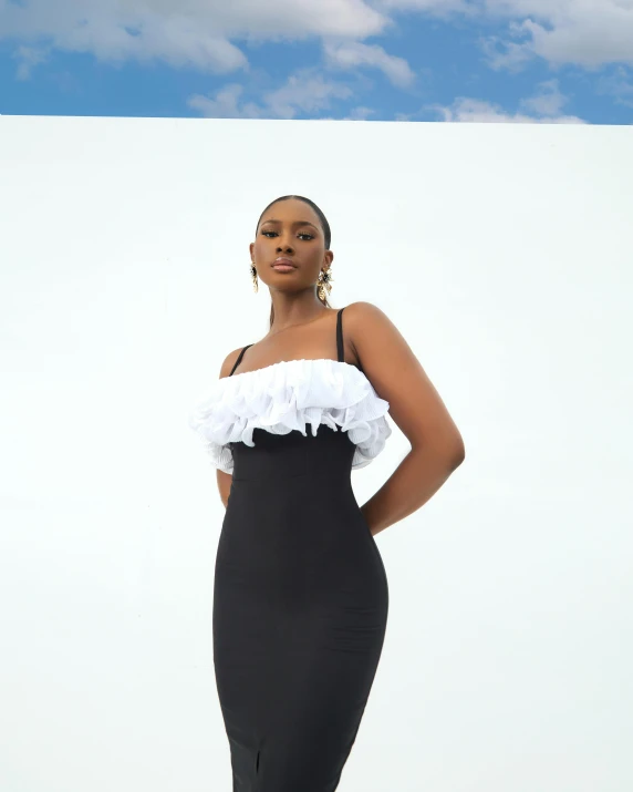 a woman in black and white clothing, standing against a backdrop of white clouds