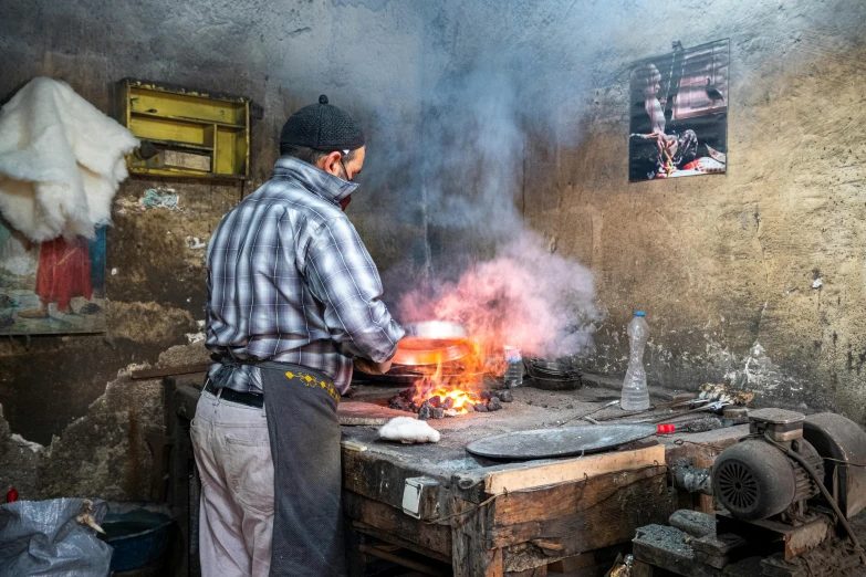 a man in plaid shirt cooking on a stove