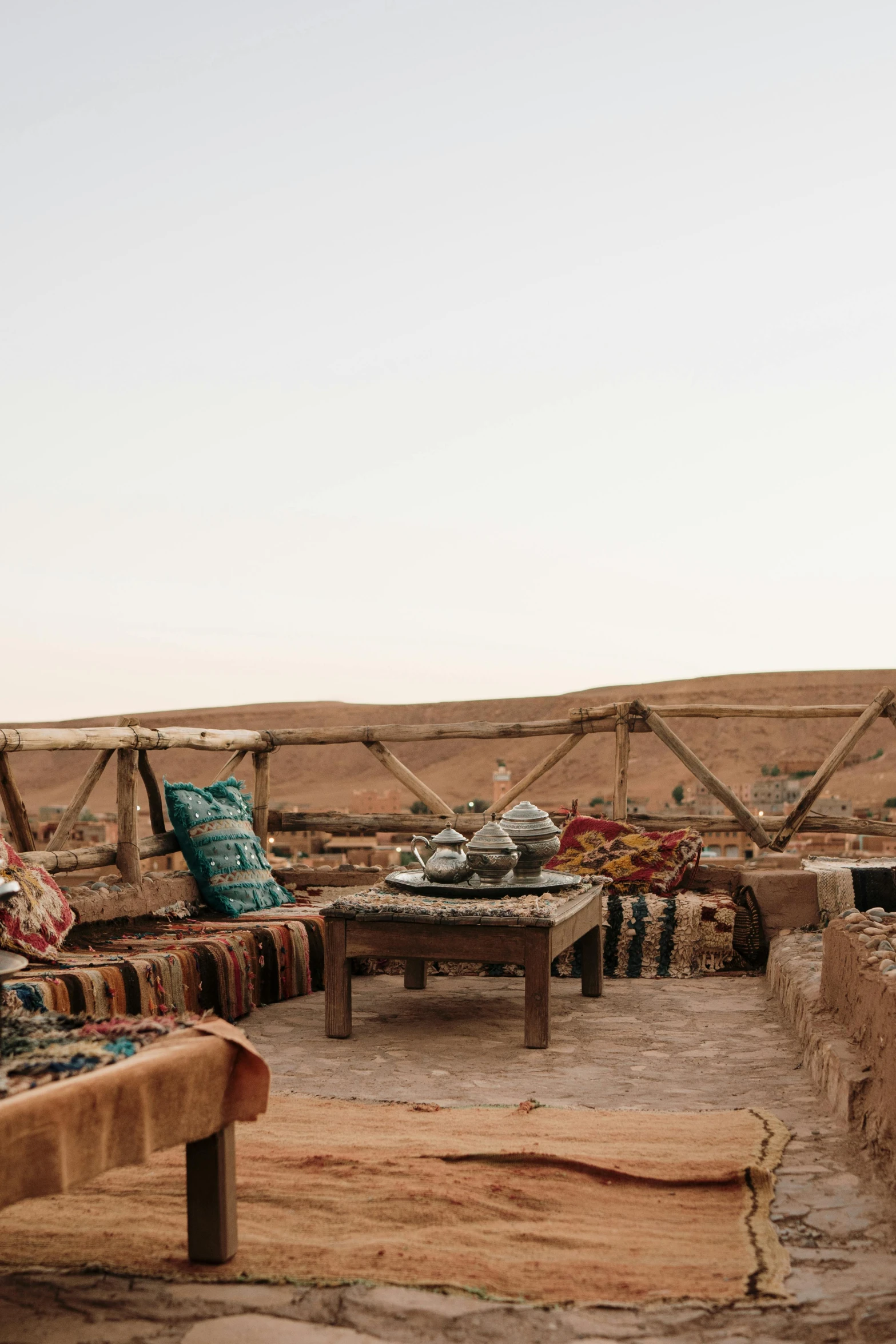 an outdoor area has two couches, some with throw pillows and several decorative tables