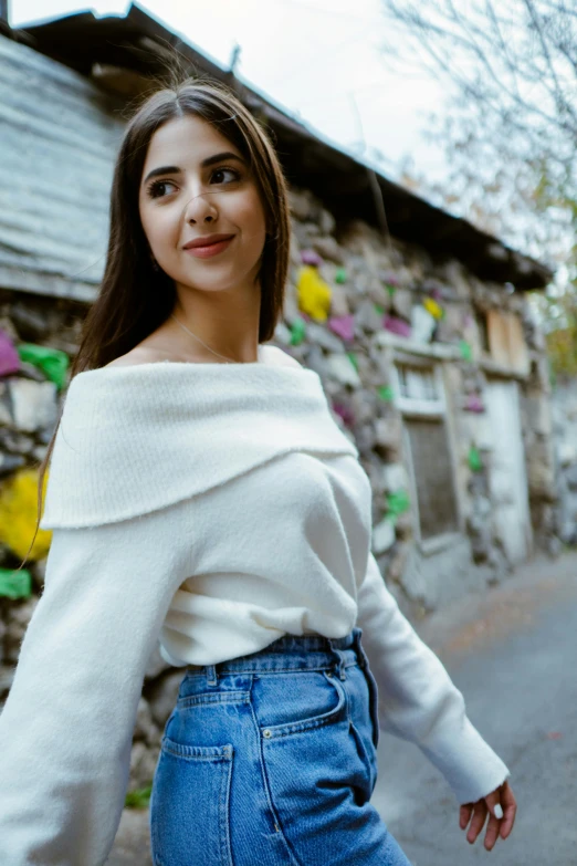 woman with long hair standing next to wall of flowers