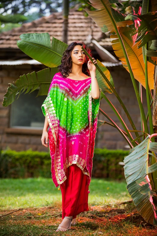 a woman with a bright dress and green shawl standing outside