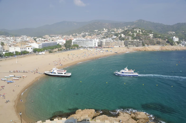 people on the beach next to boats and buildings