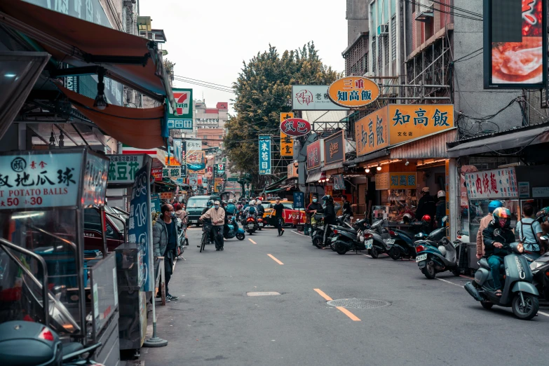 people walking and riding motorcycles down the street