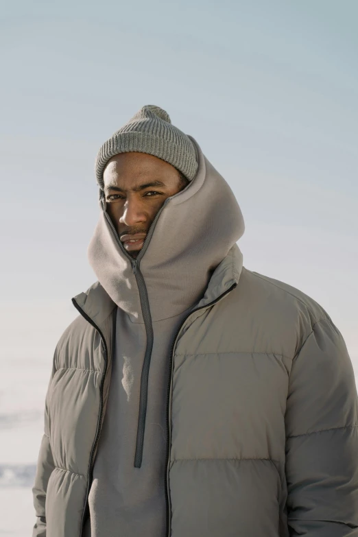 a black man in a light gray down filled jacket is outside