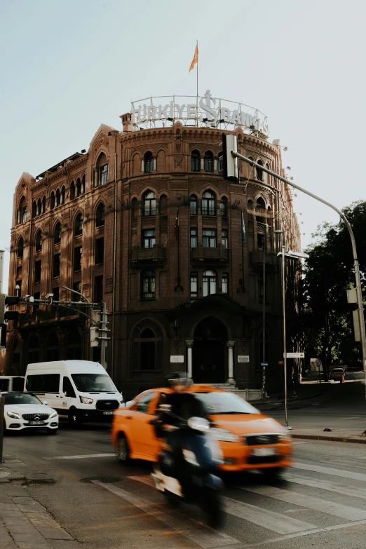 orange car and bike riding by a large building