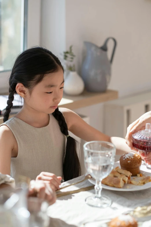 a little girl is getting a drink of wine from the adult