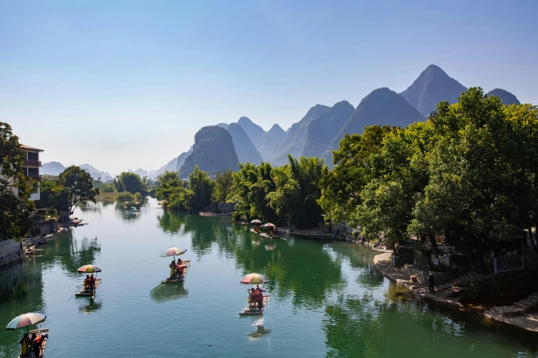 people in boats on a river between mountains