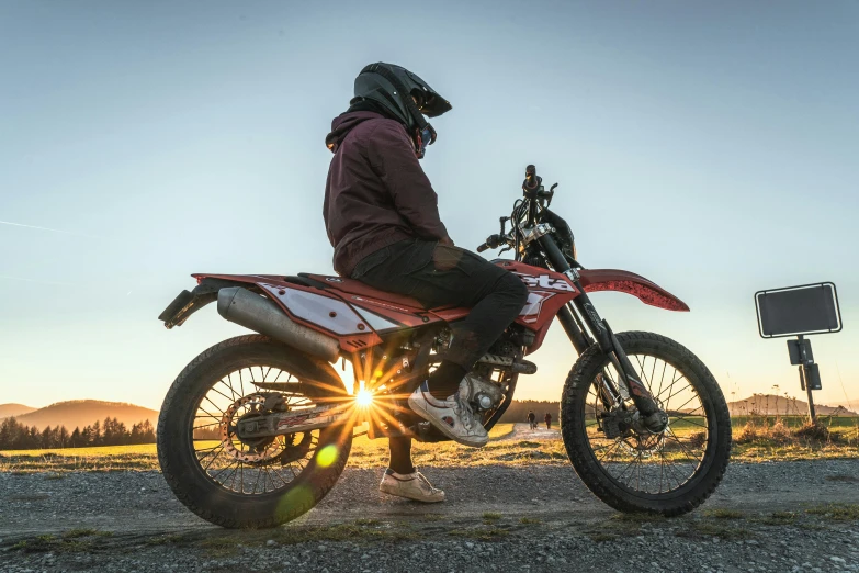 a person sitting on a dirt bike at sunset