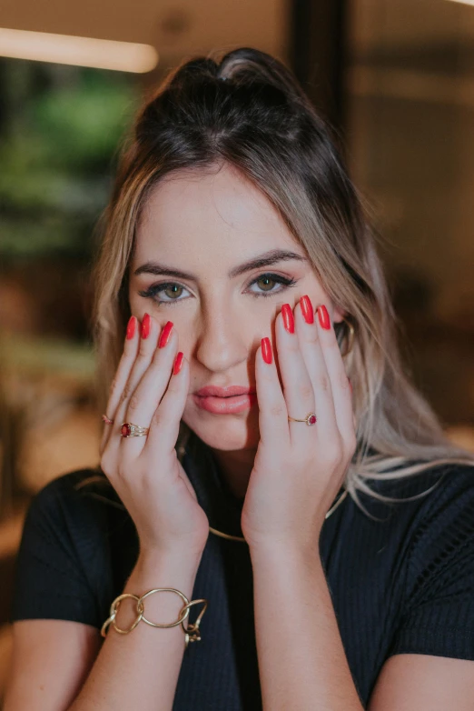 a close up of a person with red nails and makeup