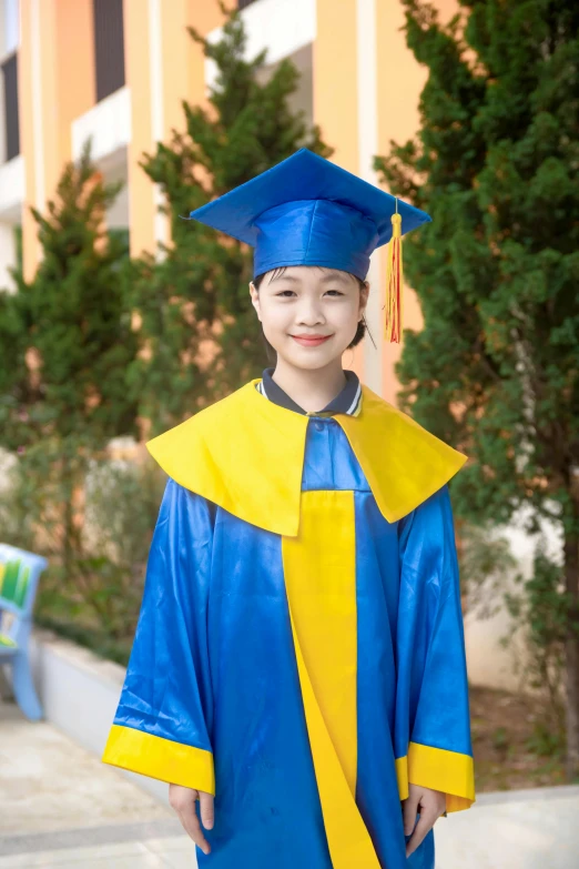 a little boy in blue and yellow graduation gown