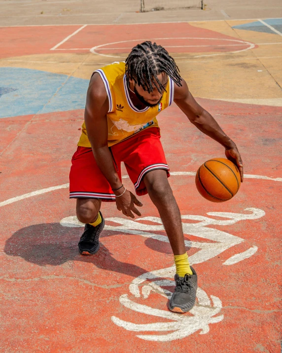 a man with dreadlocks and a basketball is bent down to dunk