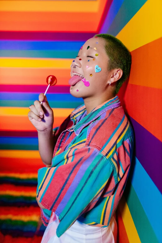 a girl is standing against a multicolored wall and smiling