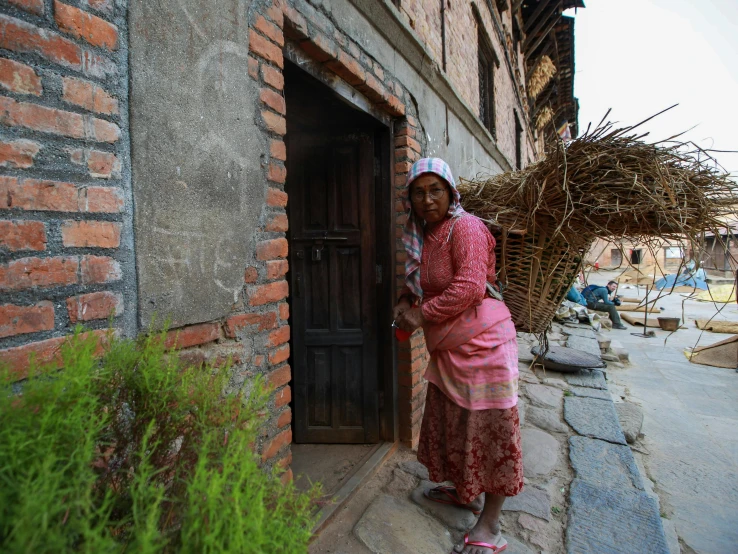 a woman is standing on a building door with bricks