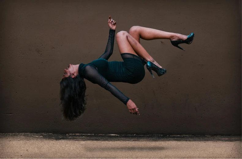 a woman upside down wearing a top and skirt with high heels