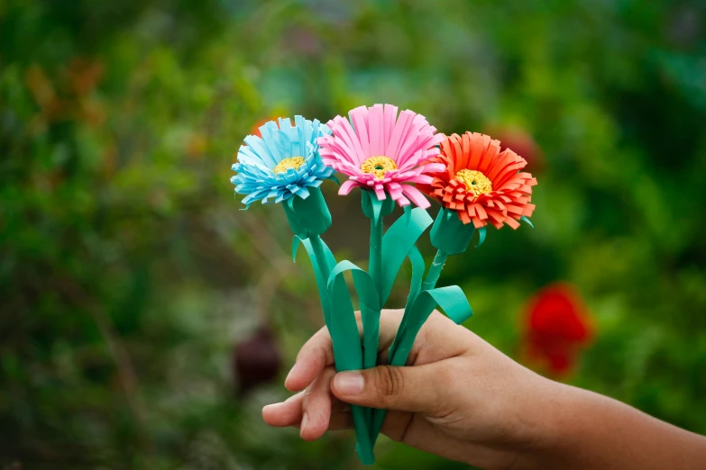 a person holding out small artificial paper flowers