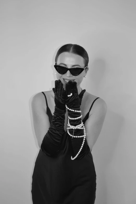 a woman in a dress and glasses with an arm length beaded glove and gloves on her face