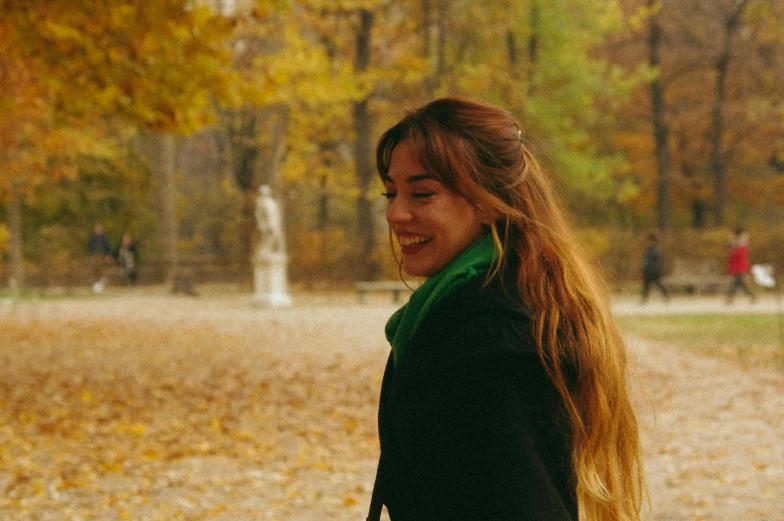 a woman standing in the park looking at soing