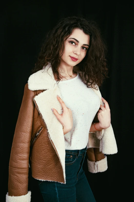 a woman with long curly hair and a white sweater posing for the camera