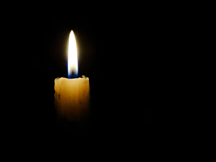 a lit candle in the dark with the light on