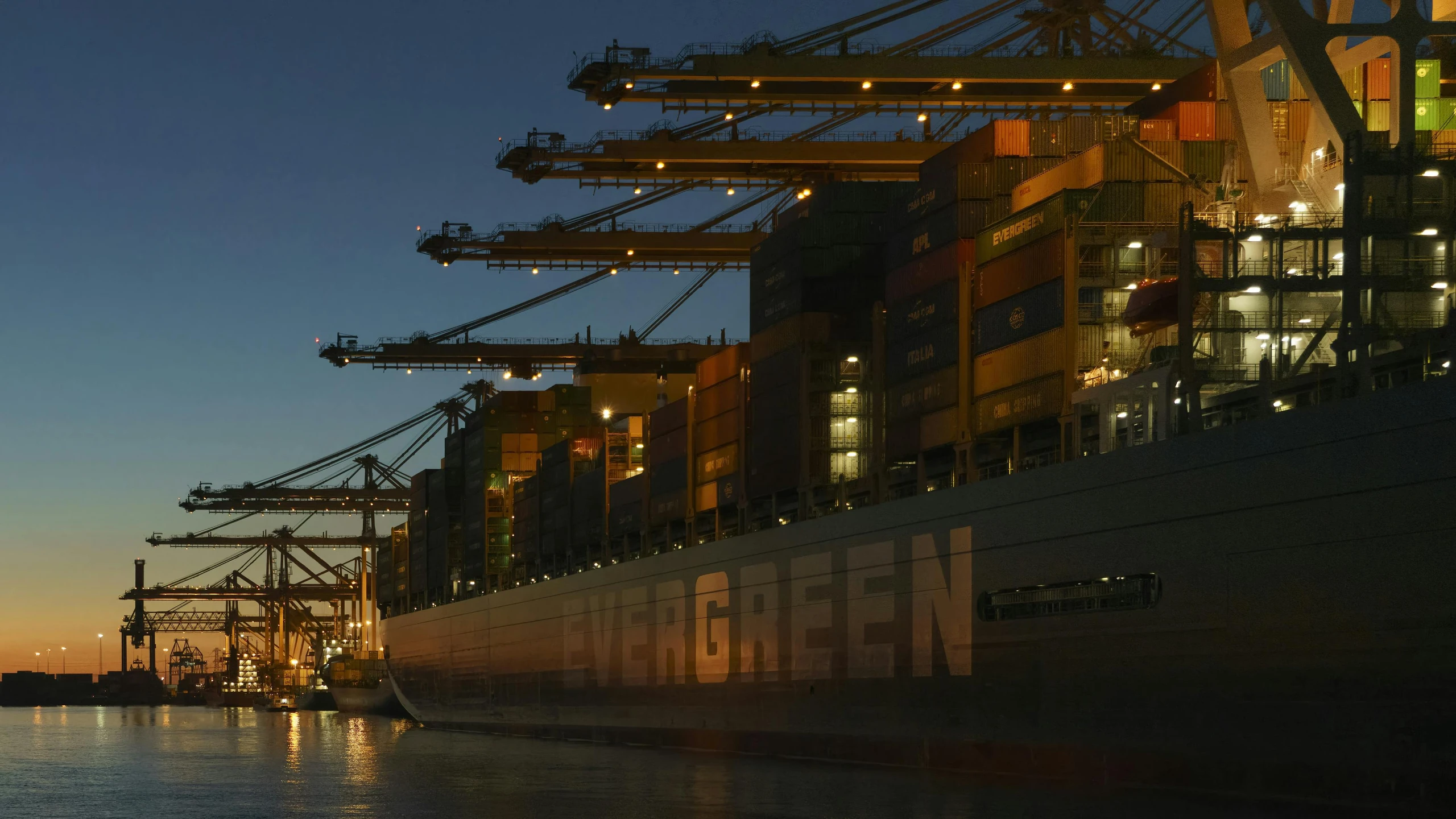 a ship docked at the ocean with many cranes