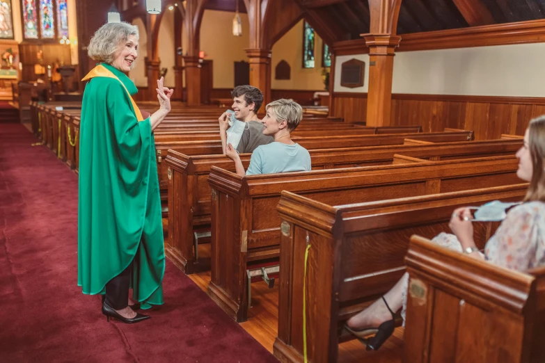 a woman standing at the end of a pew as two young children sit