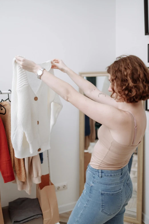 a lady showing off her sweater in her bedroom