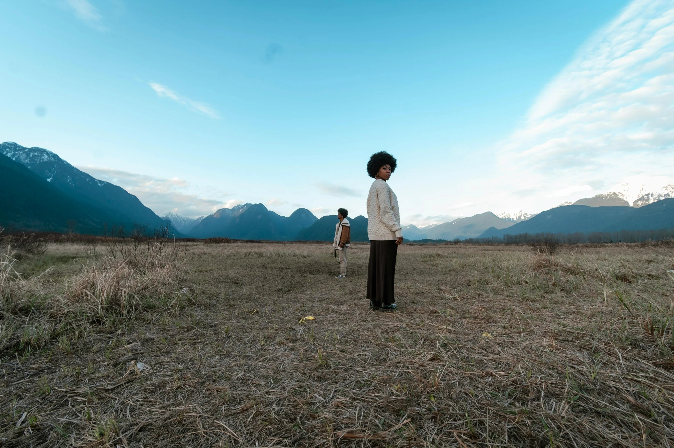 there are two women in a field with some grass