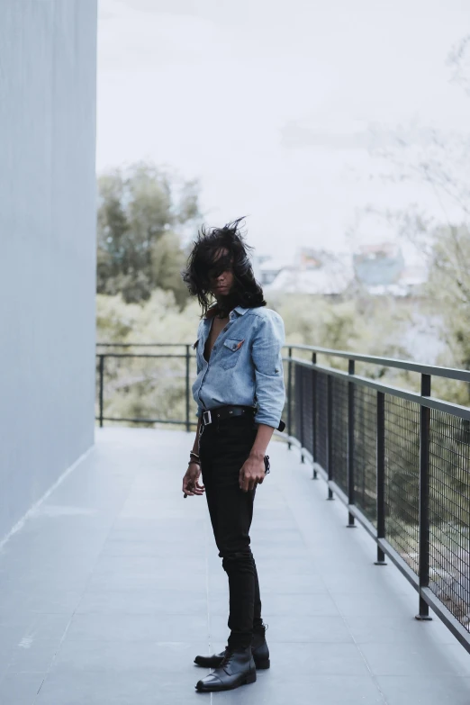 a girl wearing black clothes and boots posing on a bridge