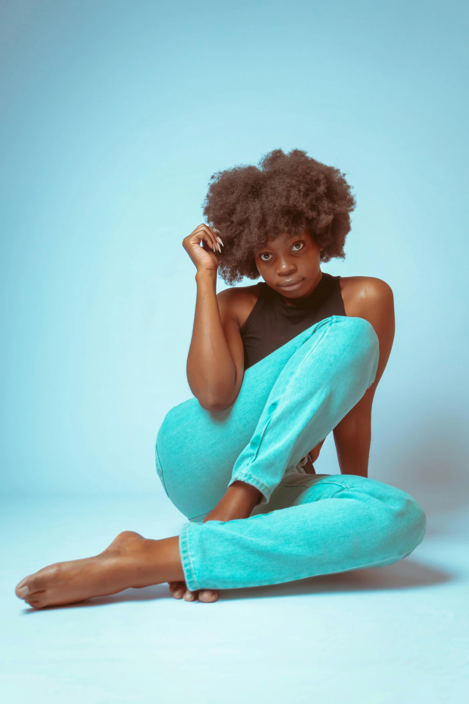 young african woman posing for a studio po wearing teal pants