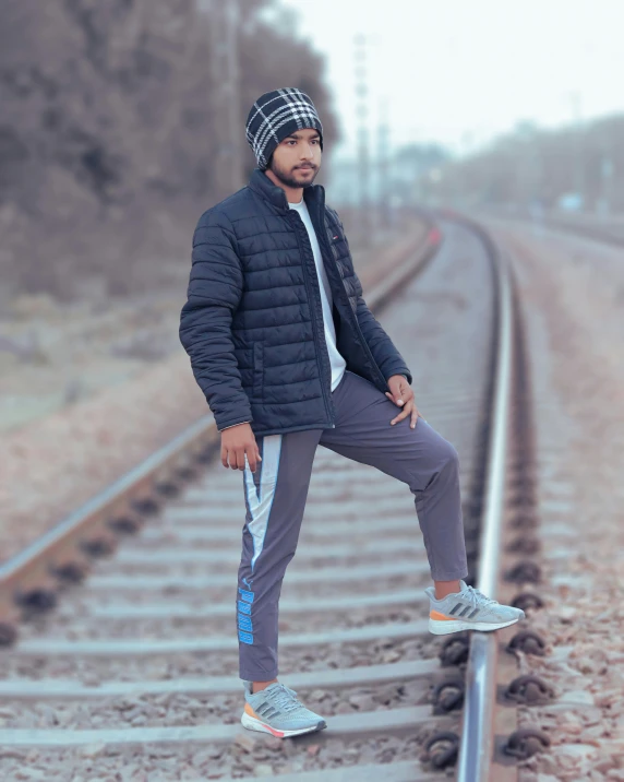 man posing on railroad tracks on a cold day