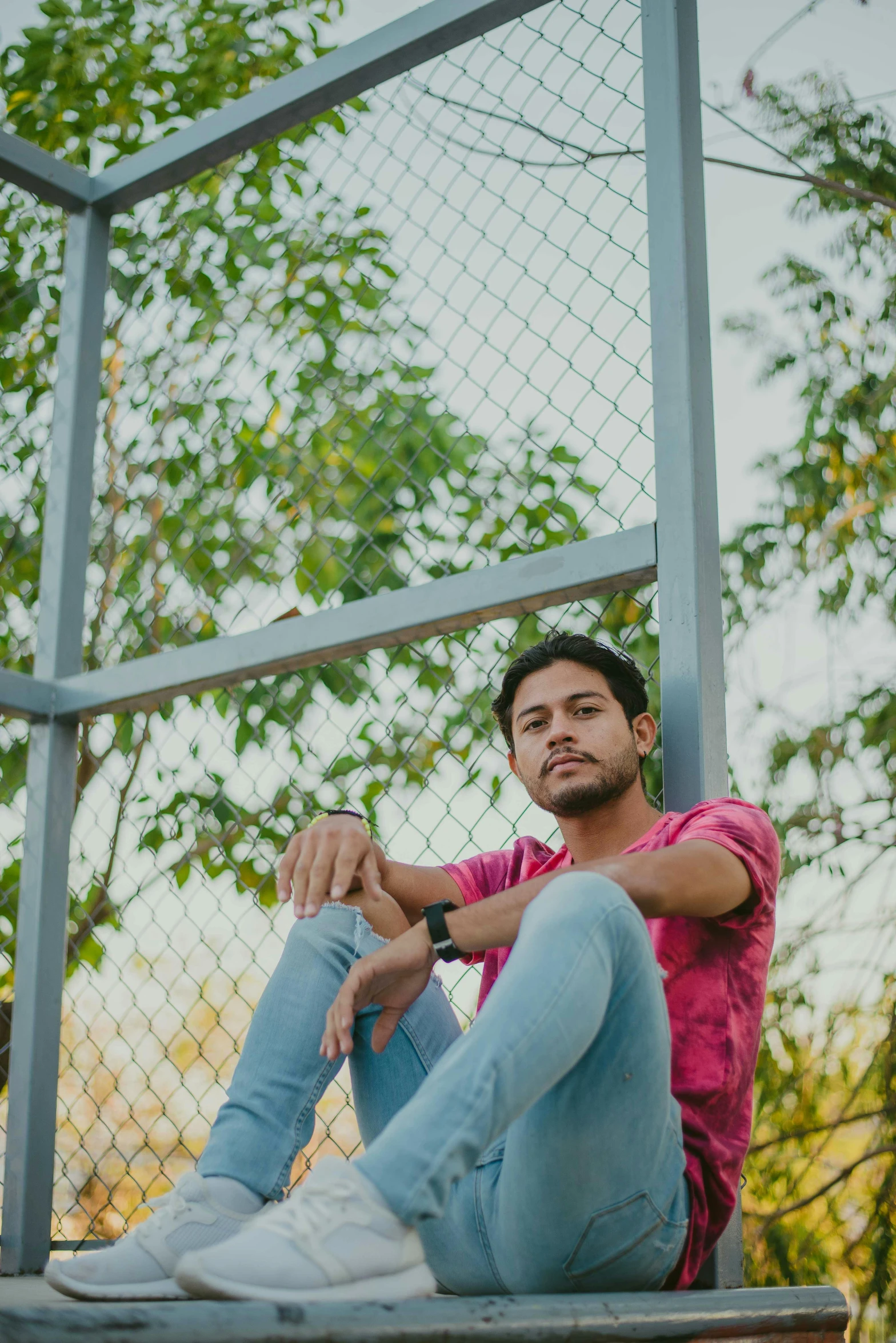 the man sits on a metal platform in front of the trees