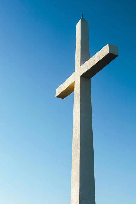 the large cement cross is in front of the sky