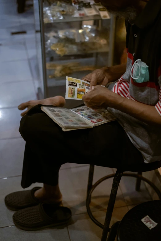 an older man sitting down while reading a newspaper