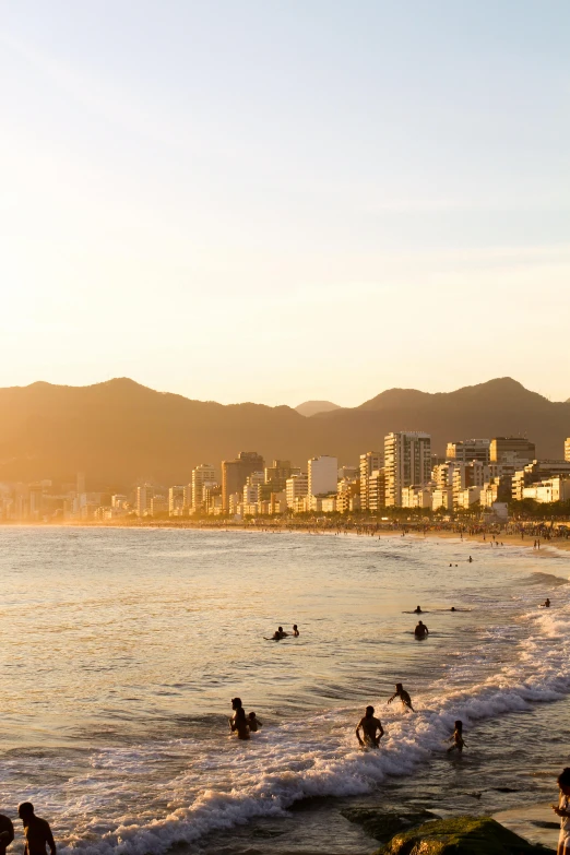 people swimming and standing on the beach