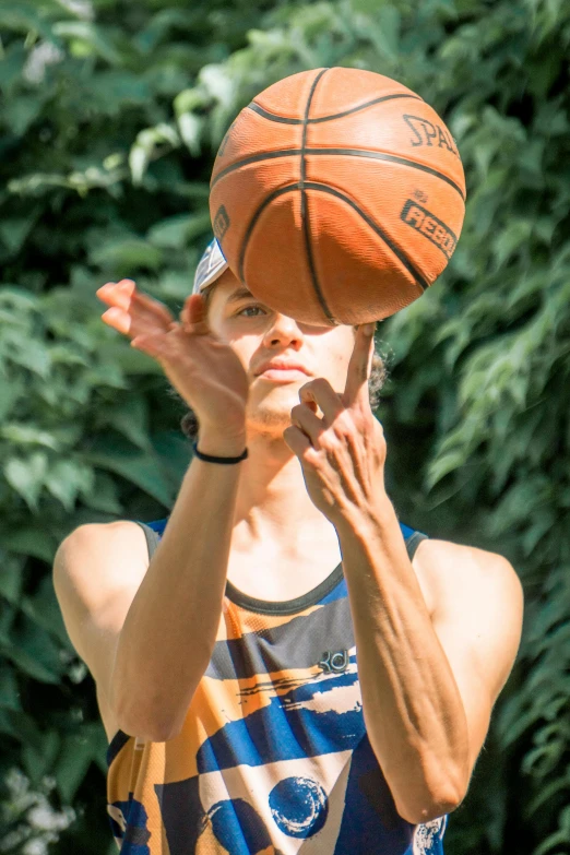 a man holding a basketball over his face