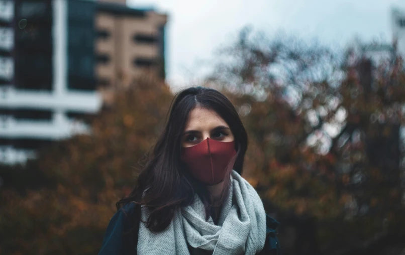 woman with a black scarf, grey coat and red mask