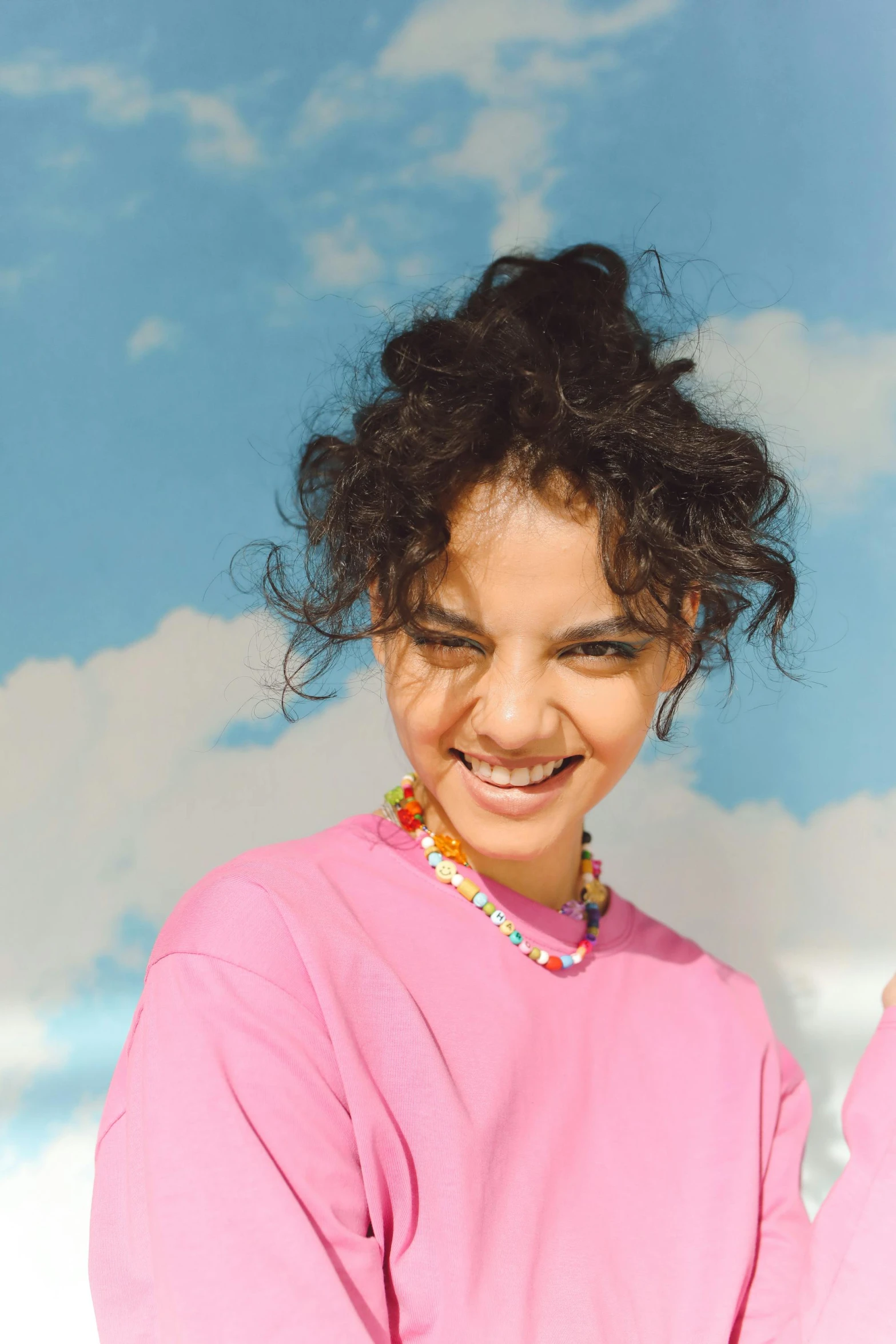 a woman smiling and wearing a pink shirt with a large round head