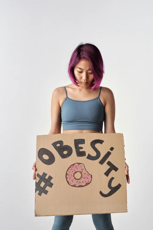 a girl is holding a cardboard sign with doughnuts on it