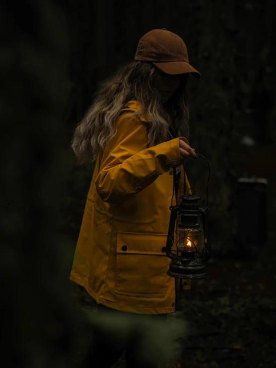 a woman wearing a yellow jacket is holding a lantern