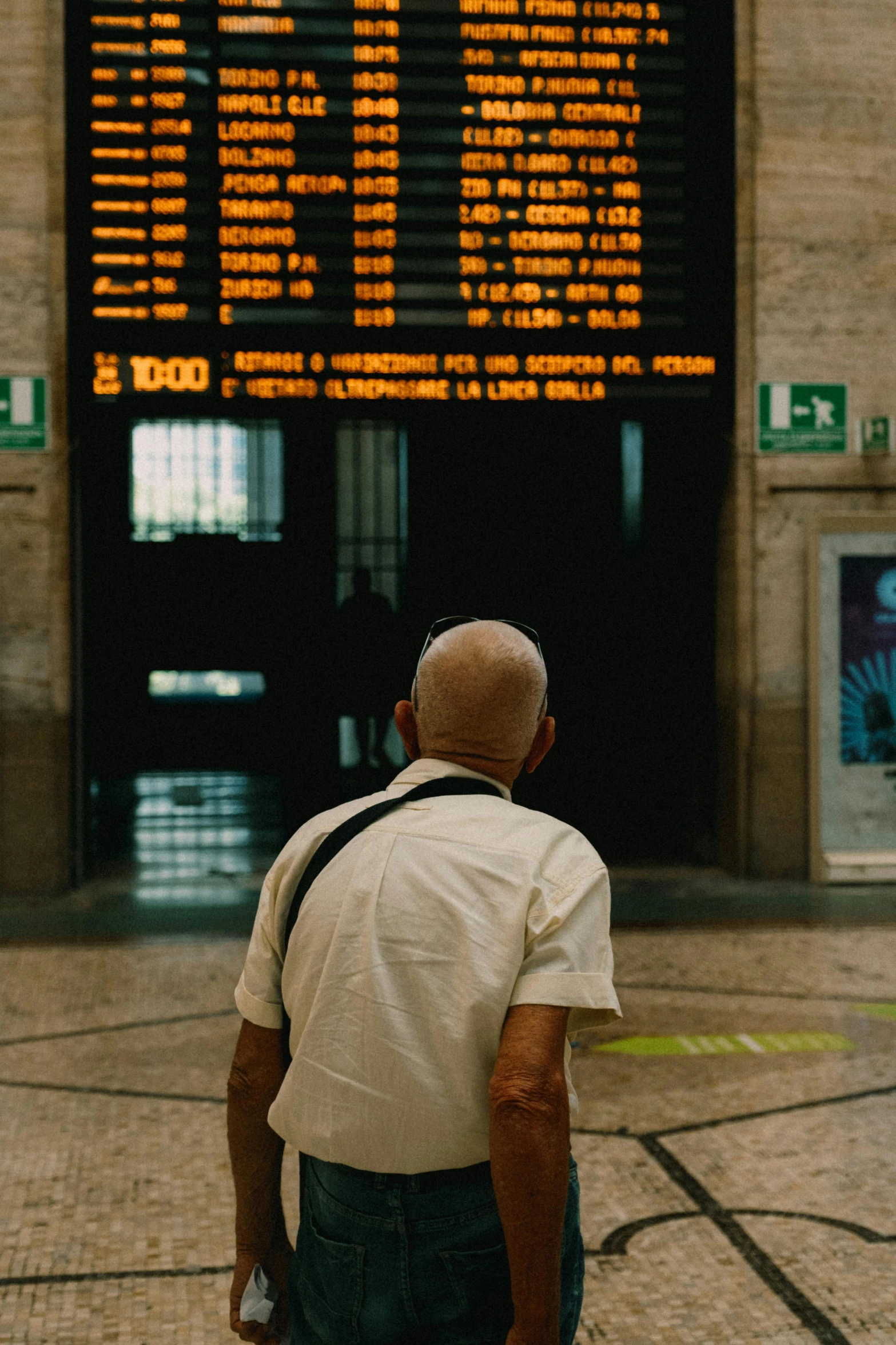 a man is watching an airport sign that tells time in roman numerals