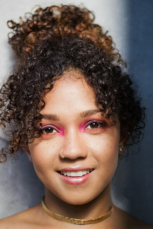 a woman with brown hair and bright makeup is smiling for the camera