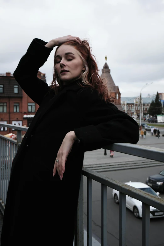 a woman standing by a rail outside in a black dress