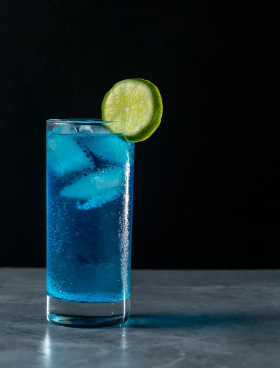 a glass of alcohol on a table with a lime slice in it