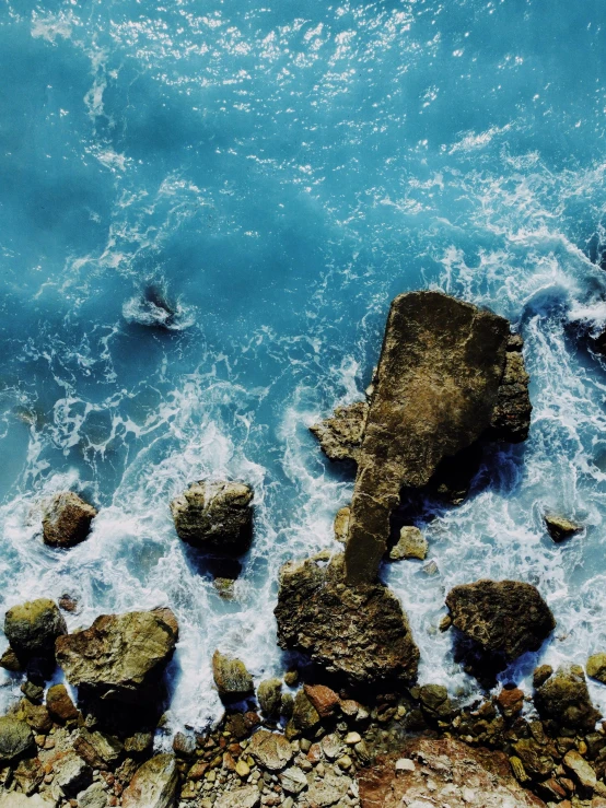 a view from a cliff over the ocean with waves crashing on rocks