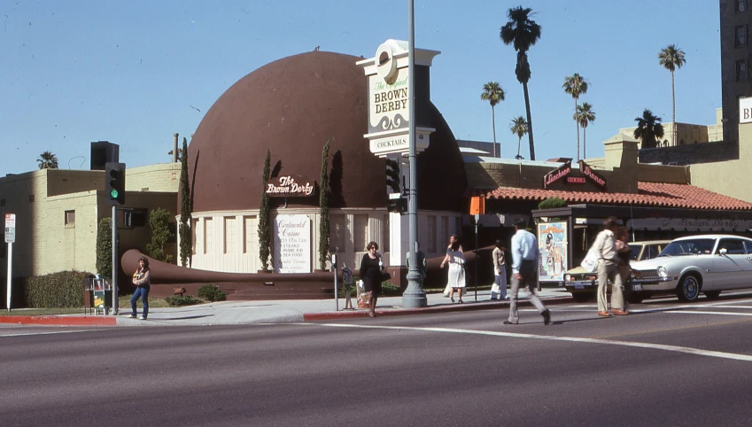 people walking on a street corner in front of a building